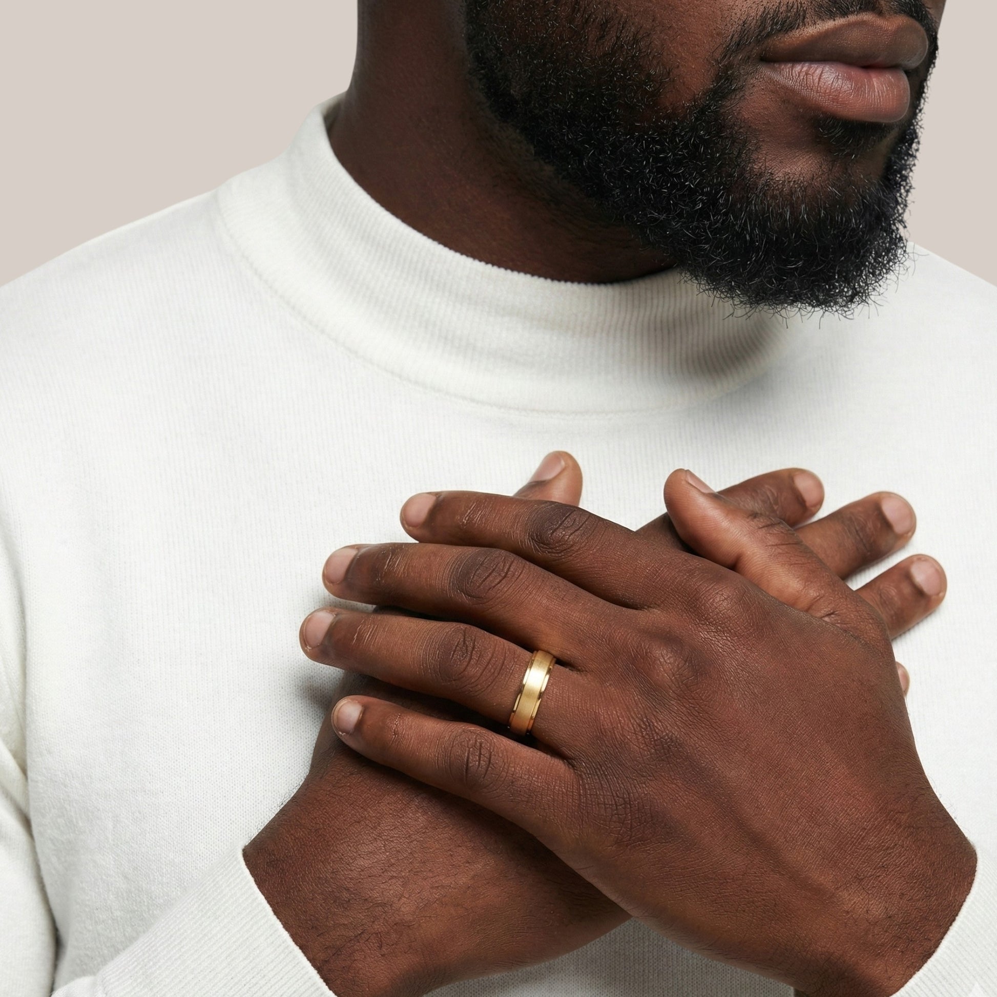 Man wearing a gold ring with a plain background