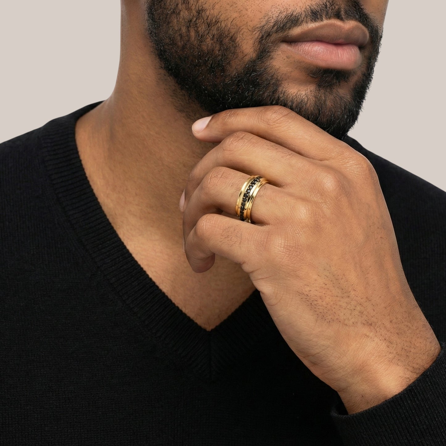 Man wearing a gold ring on his finger with a neutral background