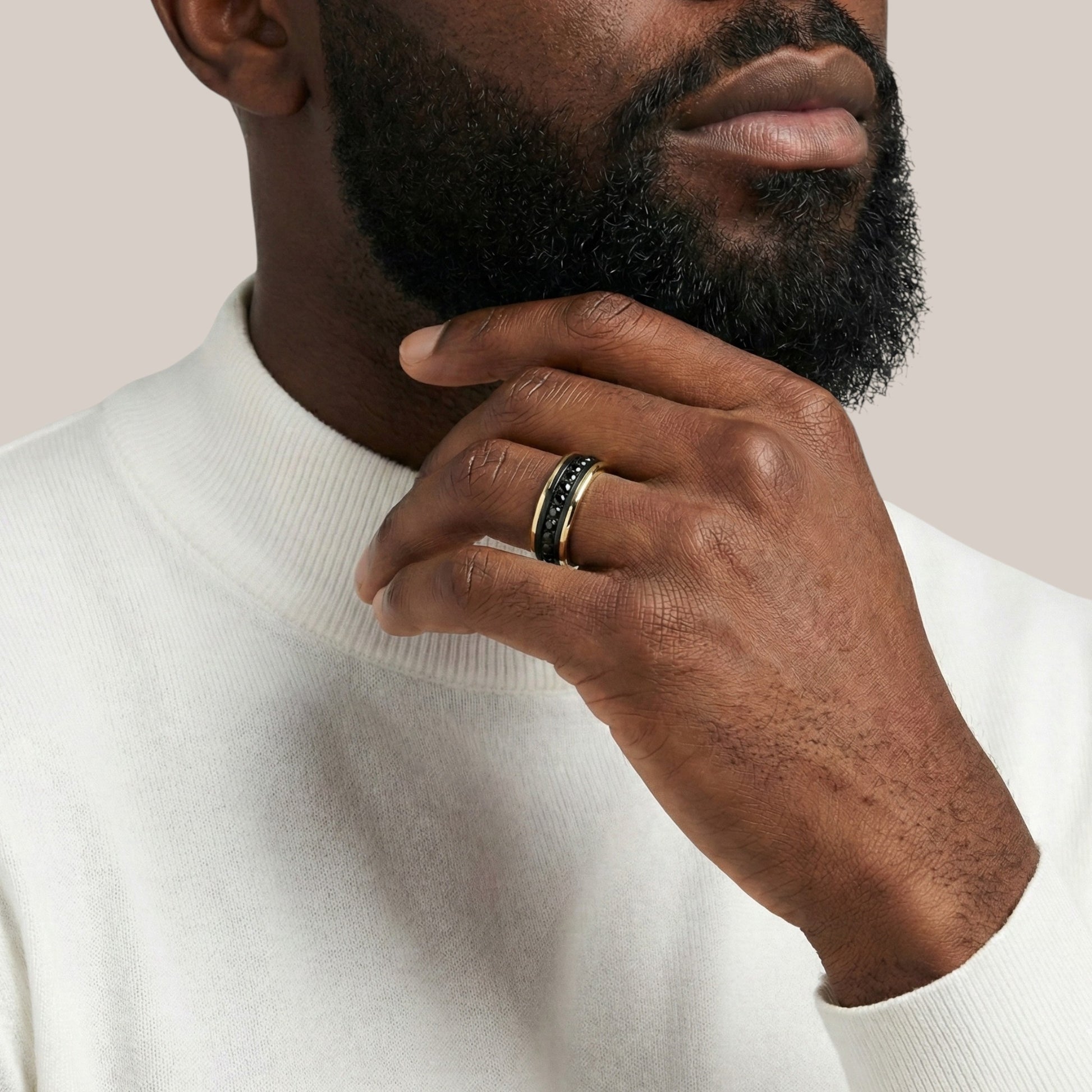Man wearing a white turtleneck sweater with a close-up of his hand and ring.