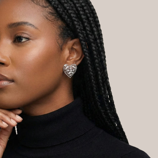 Close-up of a woman wearing a silver heart-shaped earring against a neutral background
