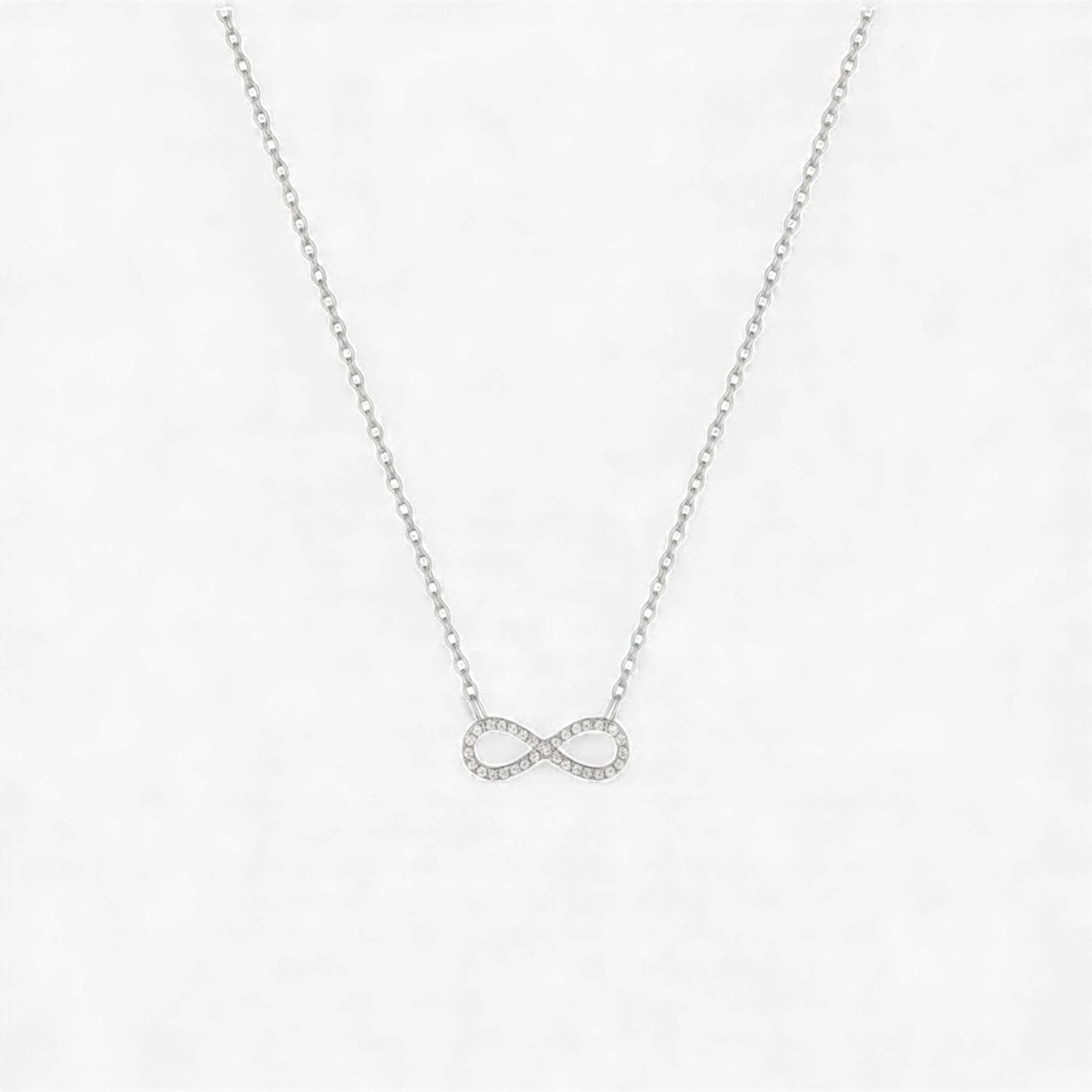 Silver infinity necklace on a light gray background