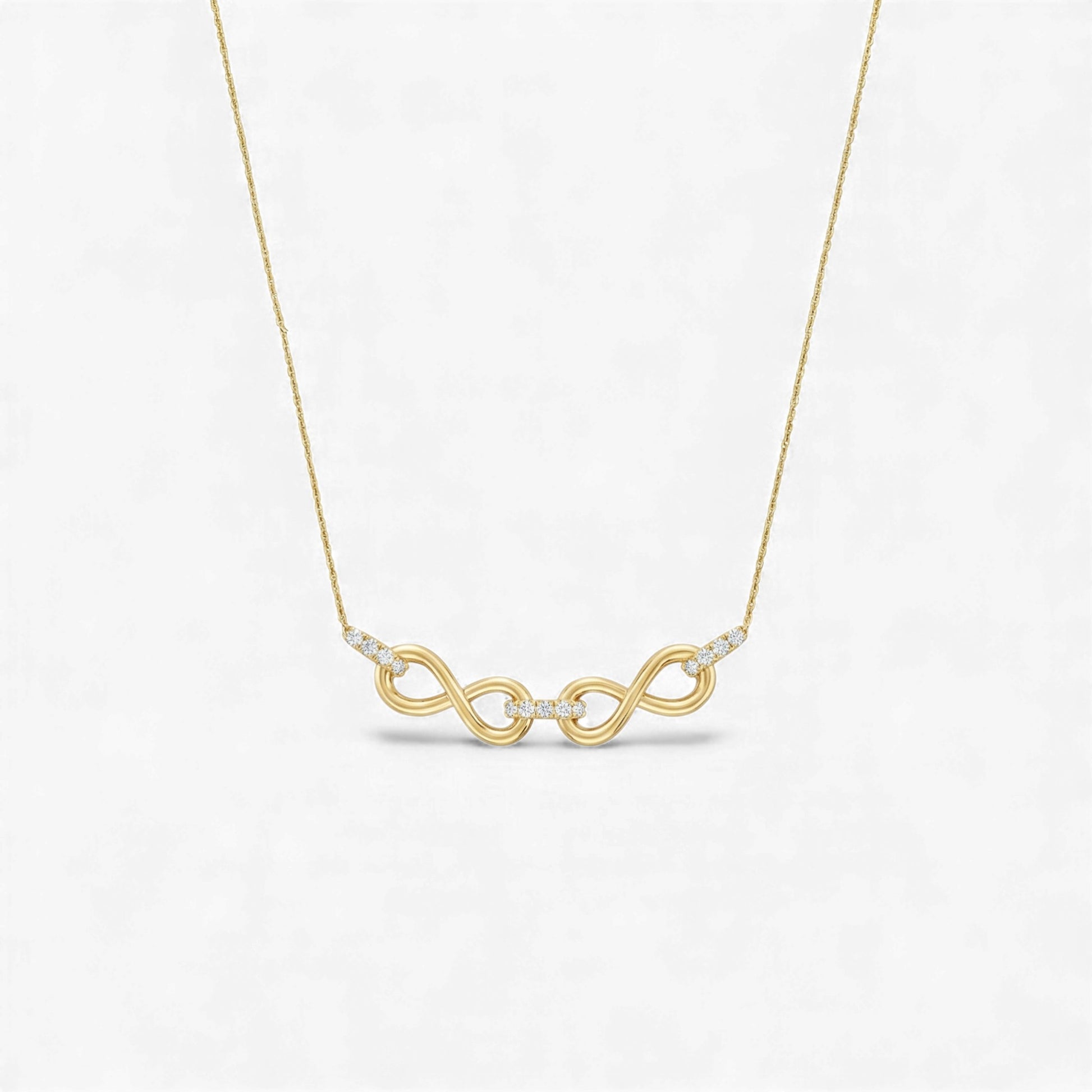 Gold necklace with a double infinity symbol pendant on a light gray background