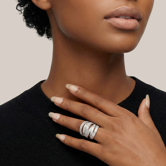 Close-up of a person wearing multiple silver rings on a neutral background