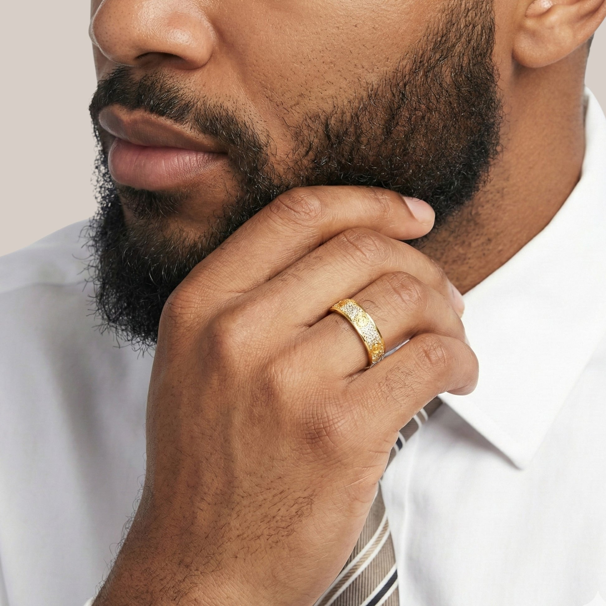 Man wearing a gold ring with a white shirt and striped tie