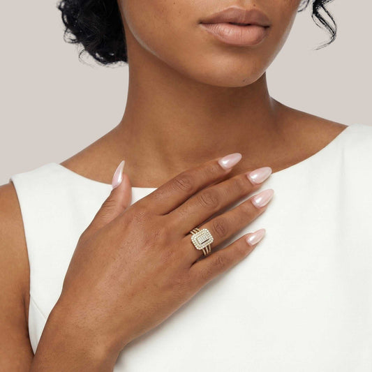 Woman wearing a gold ring with a diamond on a plain background