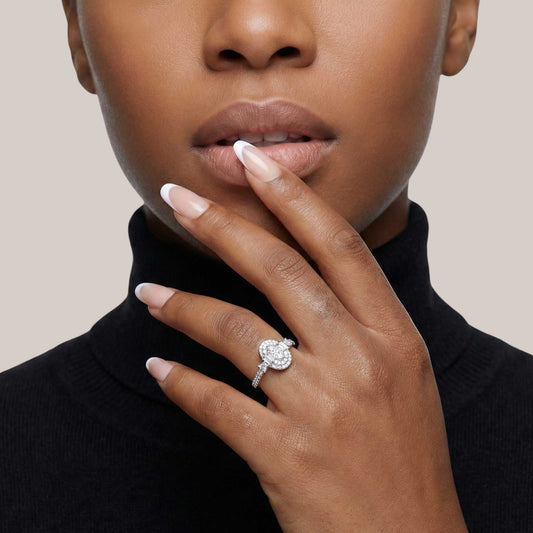Close-up of a hand wearing a diamond ring with a neutral background