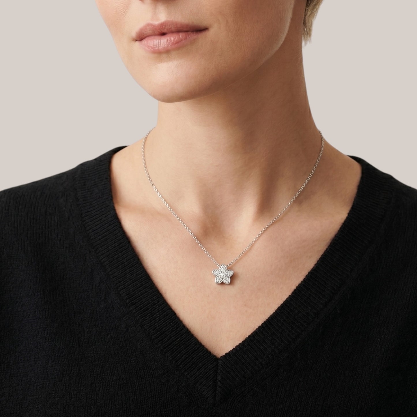 Necklace with a star-shaped pendant worn by a person in a black sweater.