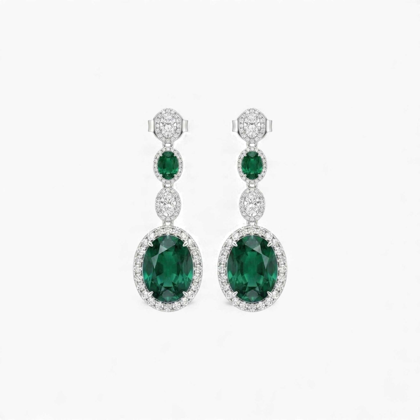 Pair of emerald and diamond earrings on a white background