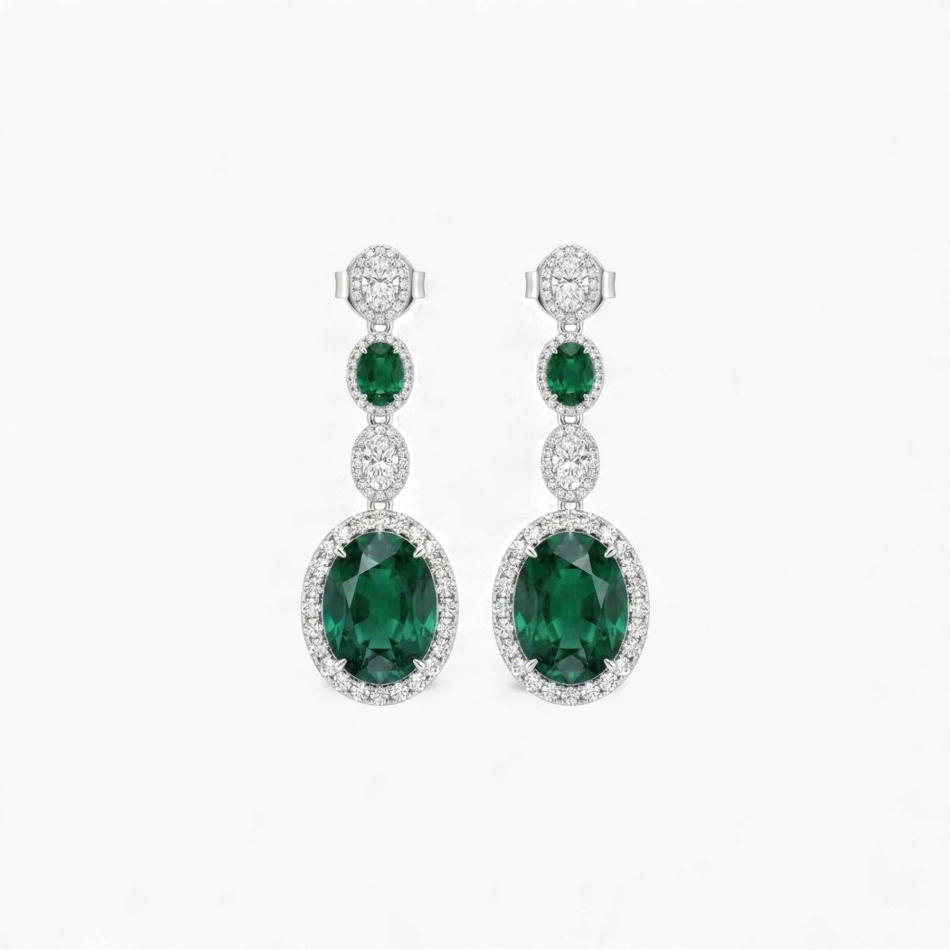 Pair of emerald and diamond earrings on a white background