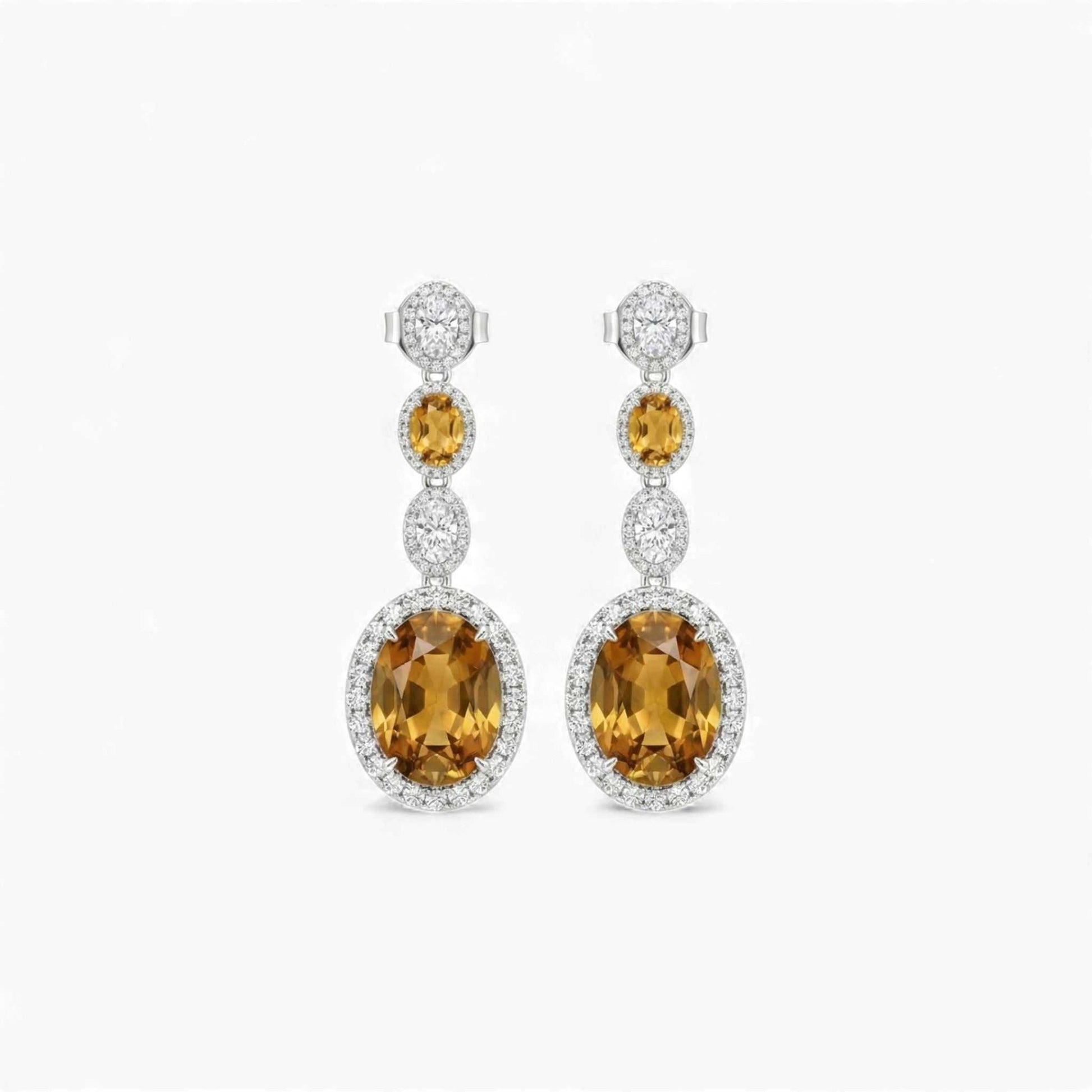 Pair of earrings with yellow gemstones and diamond accents on a white background