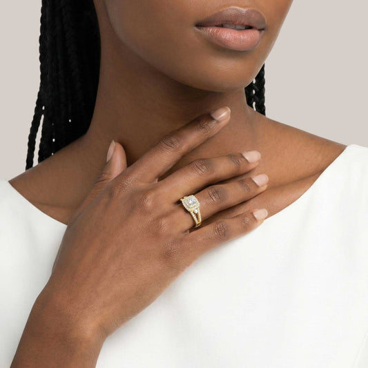Close-up of a hand wearing a gold ring with a diamond on a neutral background