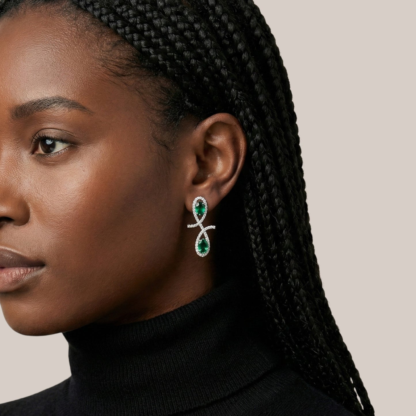 Close-up of a woman wearing green and silver earrings with braided hair.