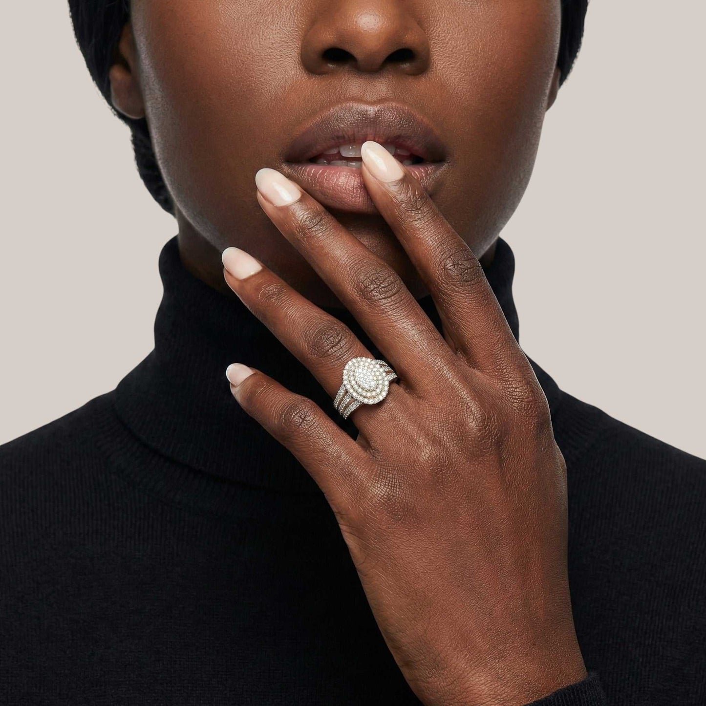 Close-up of a person wearing a ring with a beige background