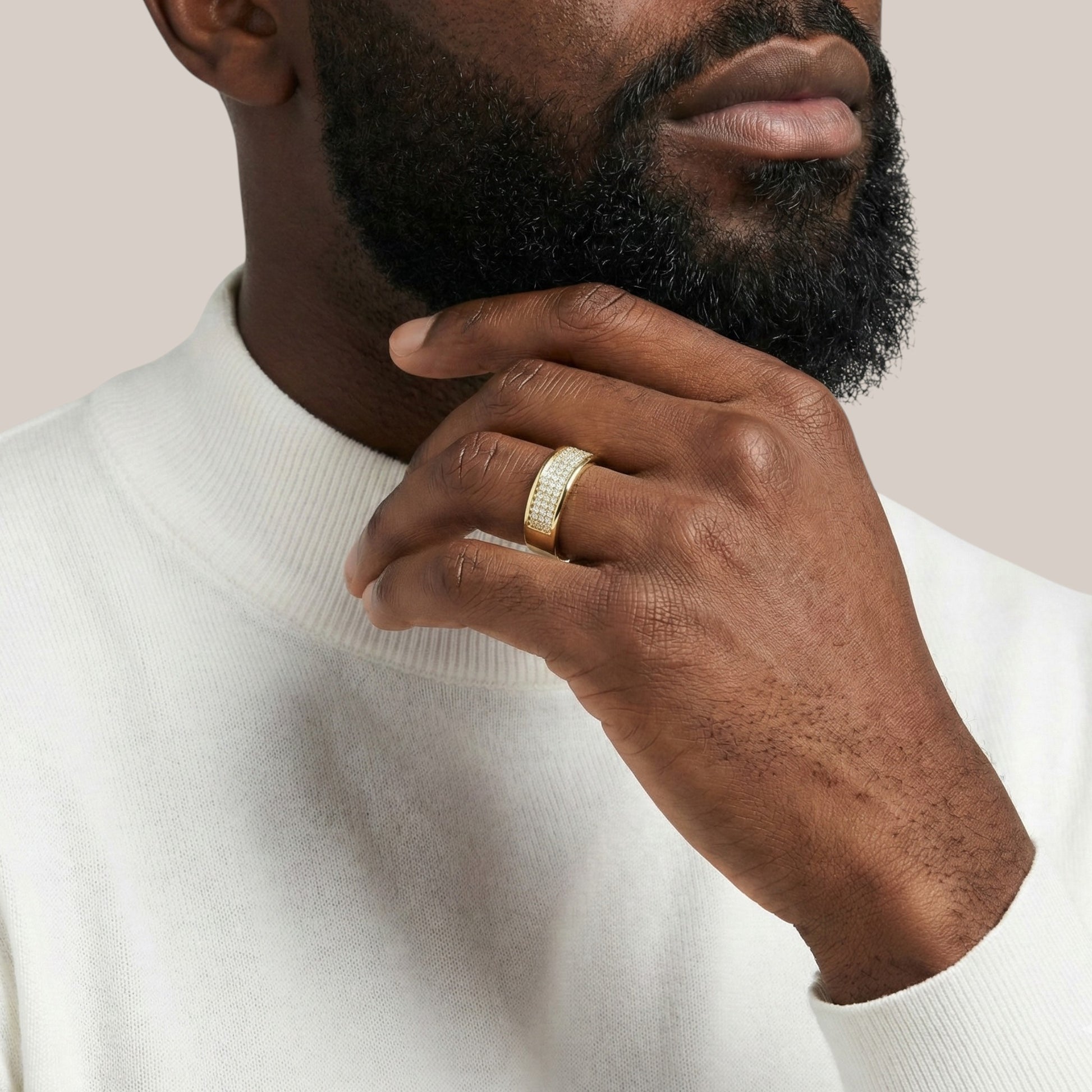 Man wearing a gold ring on his hand, with a neutral background