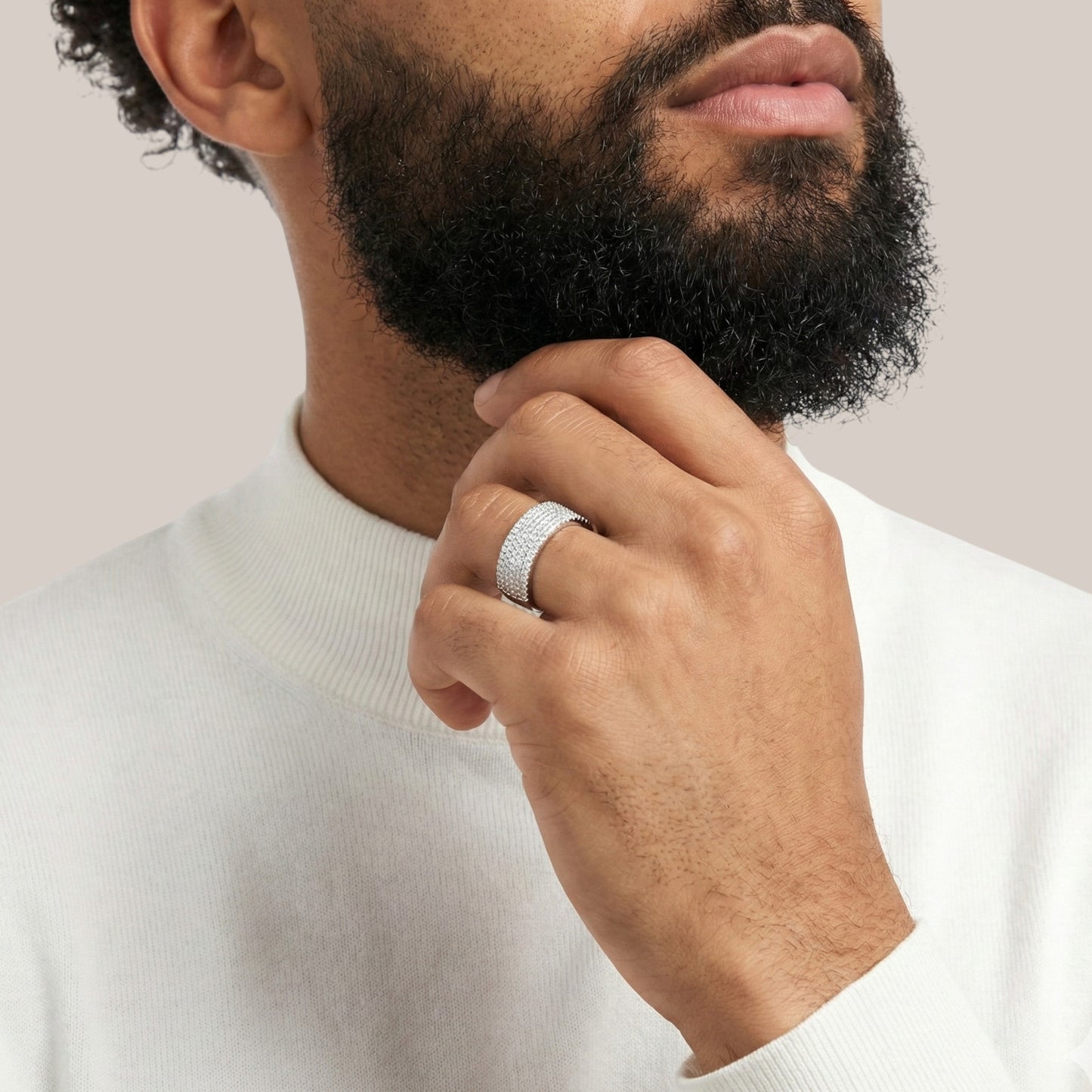 Man wearing a silver ring on his finger, with a neutral background