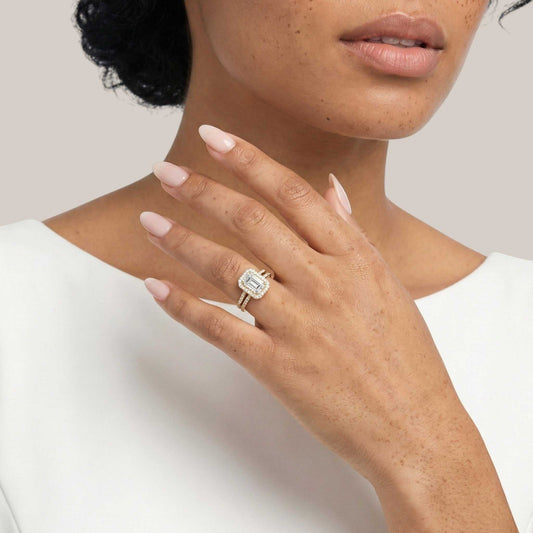 Close-up of a hand wearing a ring with a diamond on a plain background