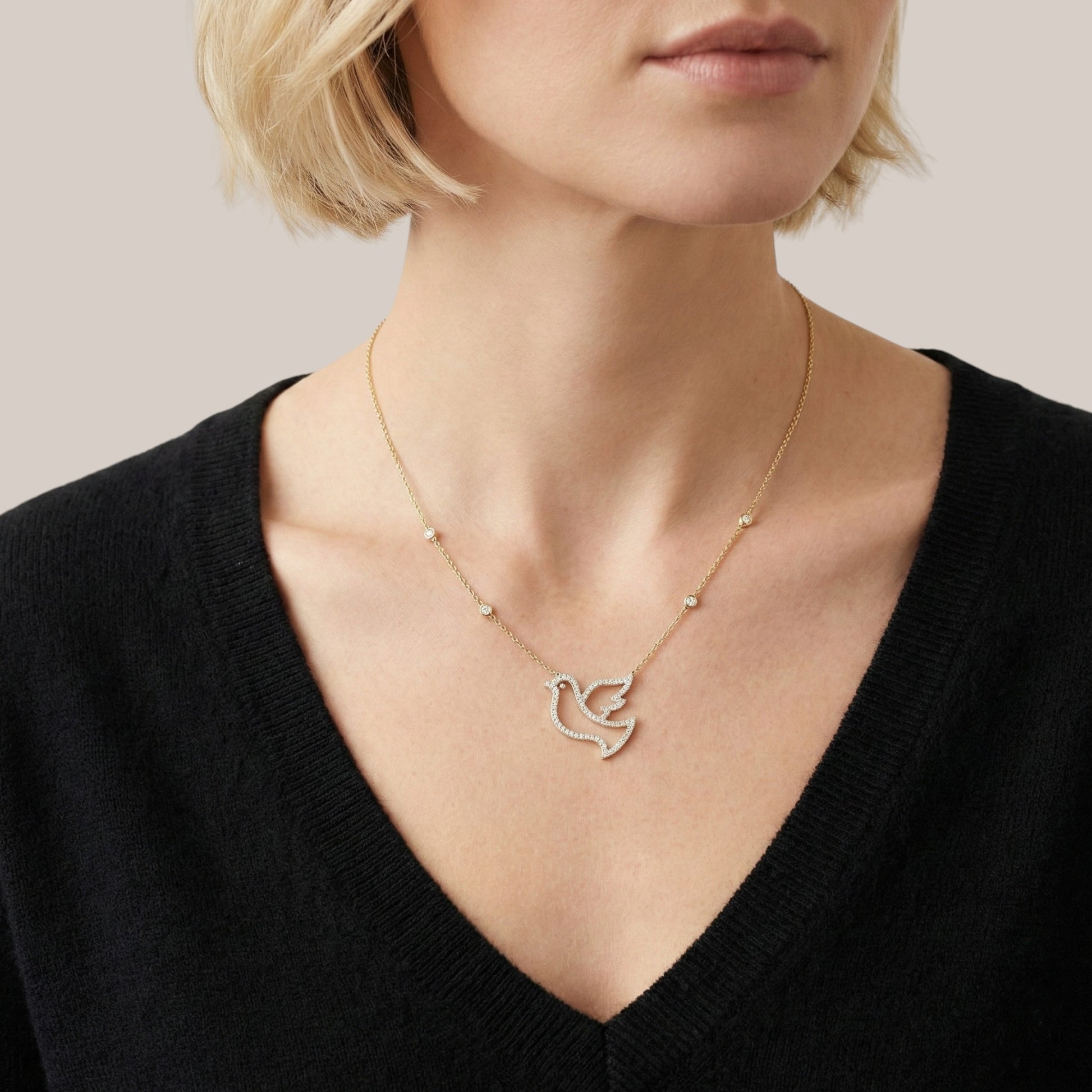 Necklace with a dove pendant worn by a person against a neutral background