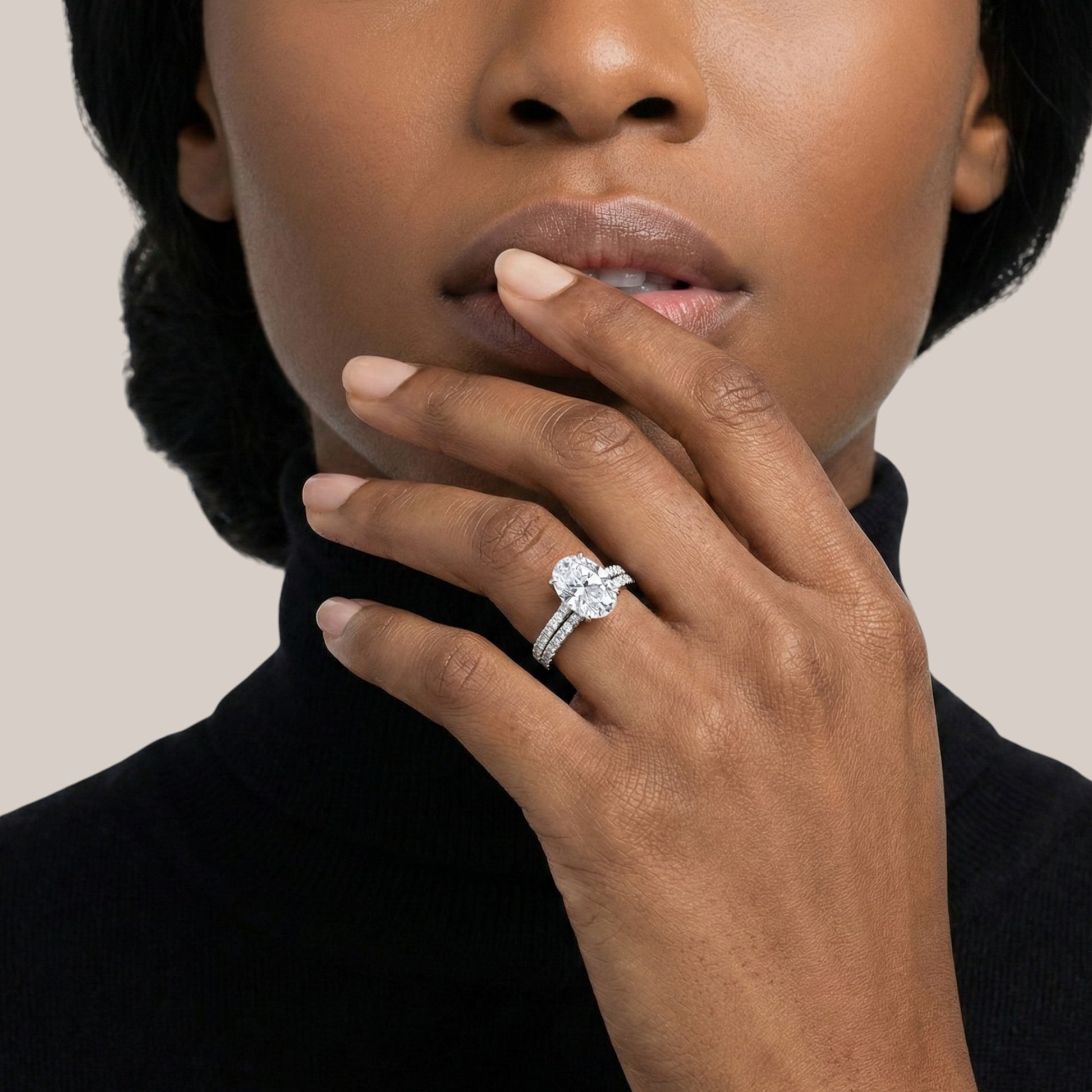 Close-up of a hand wearing a diamond ring with a neutral background