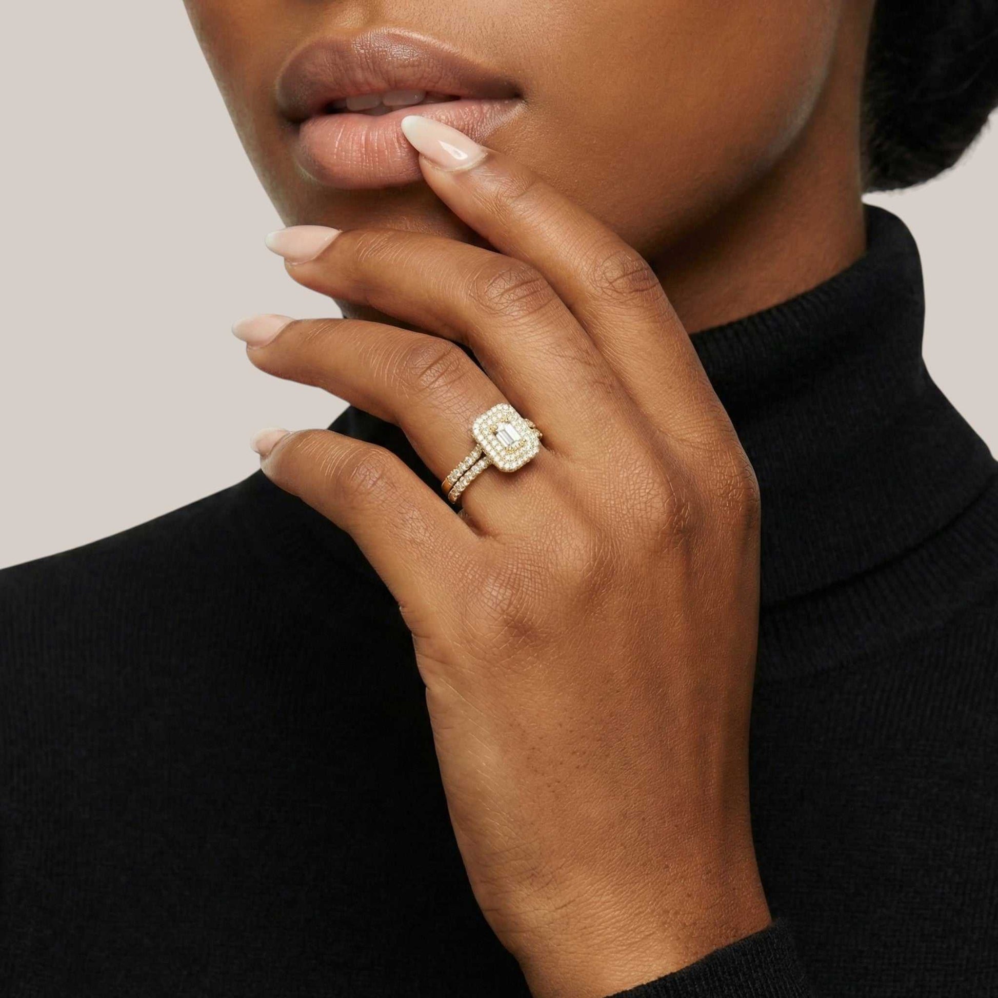 Hand wearing a diamond ring with a neutral background