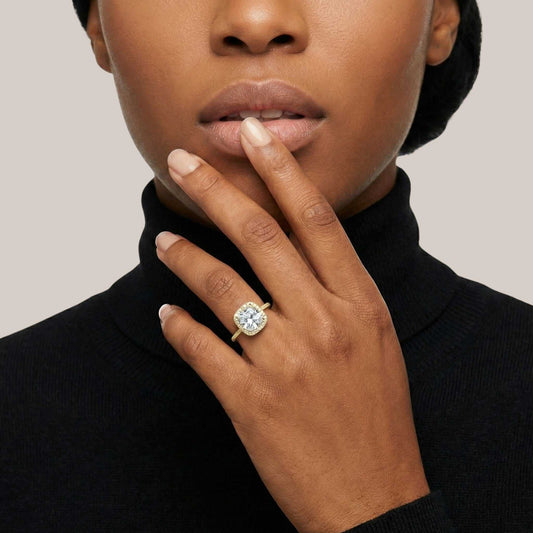 Woman wearing a gold ring with a blue gemstone on a neutral background