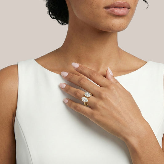 Close-up of a woman's hand wearing two diamond rings on a plain background