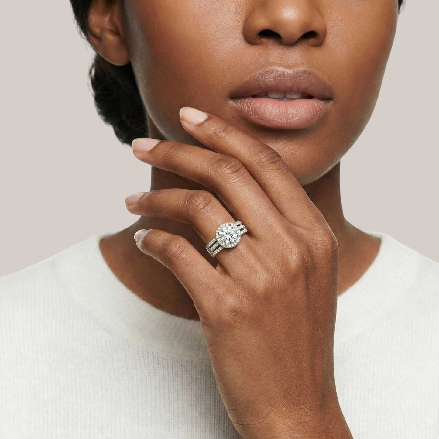 Woman wearing a diamond ring on her finger against a neutral background
