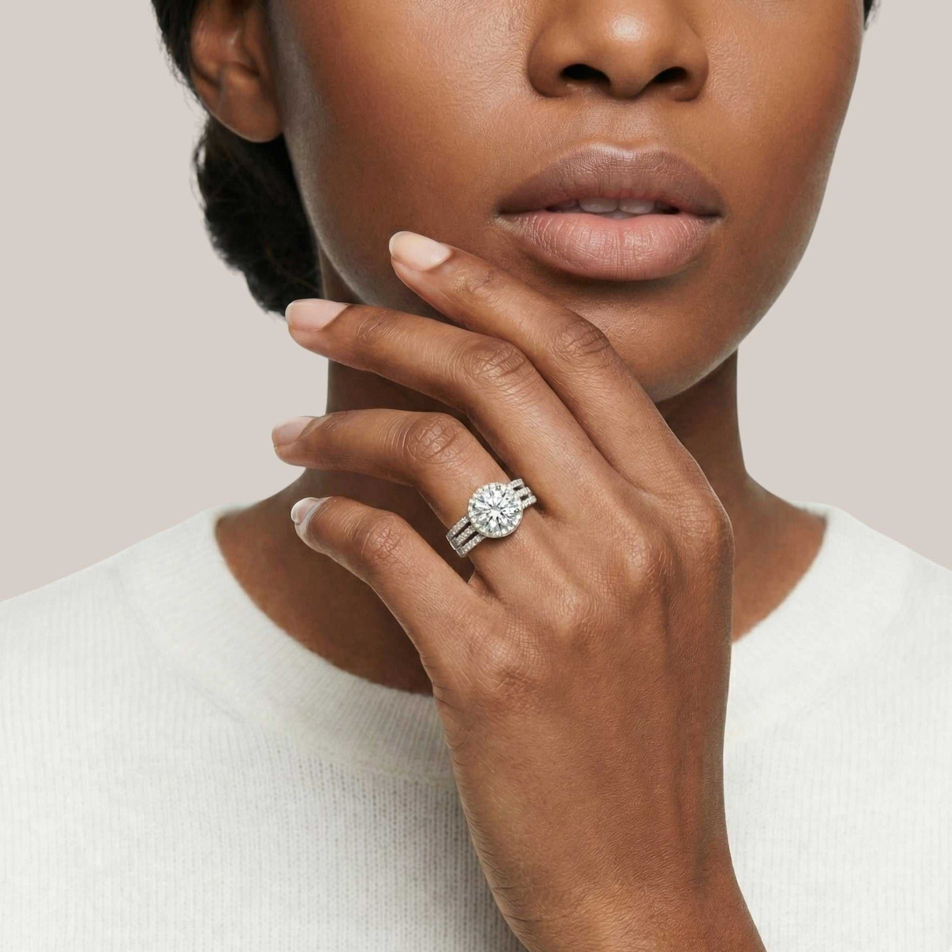 Woman wearing a diamond ring on her finger against a neutral background
