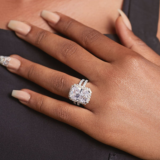 Close-up of a hand wearing a diamond ring on a dark background