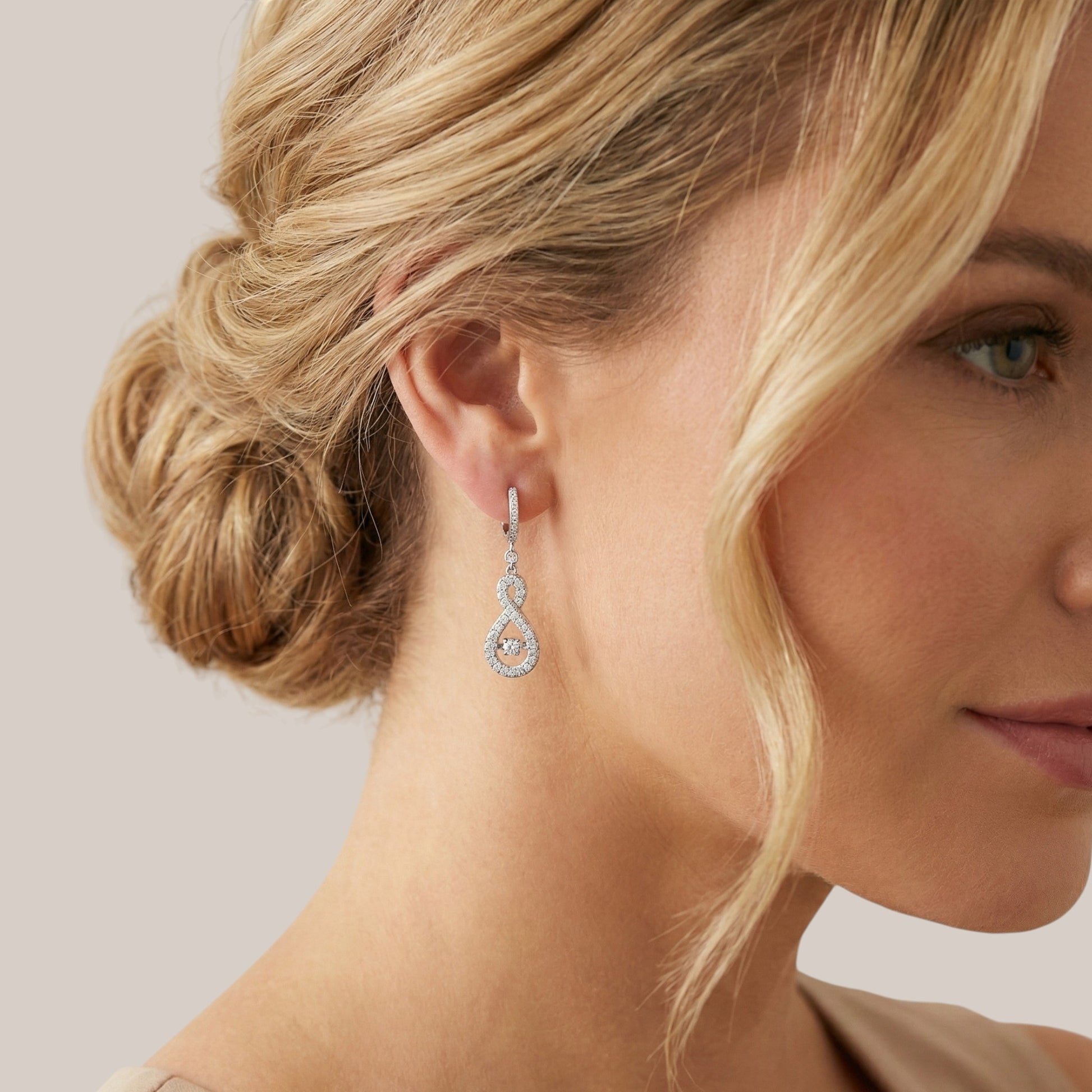 Close-up of a woman wearing a diamond earring with a neutral background