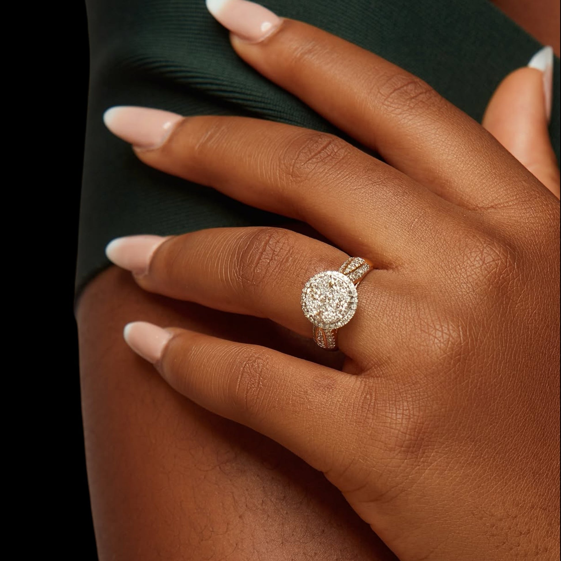 Close-up of a hand wearing a diamond ring with a dark background