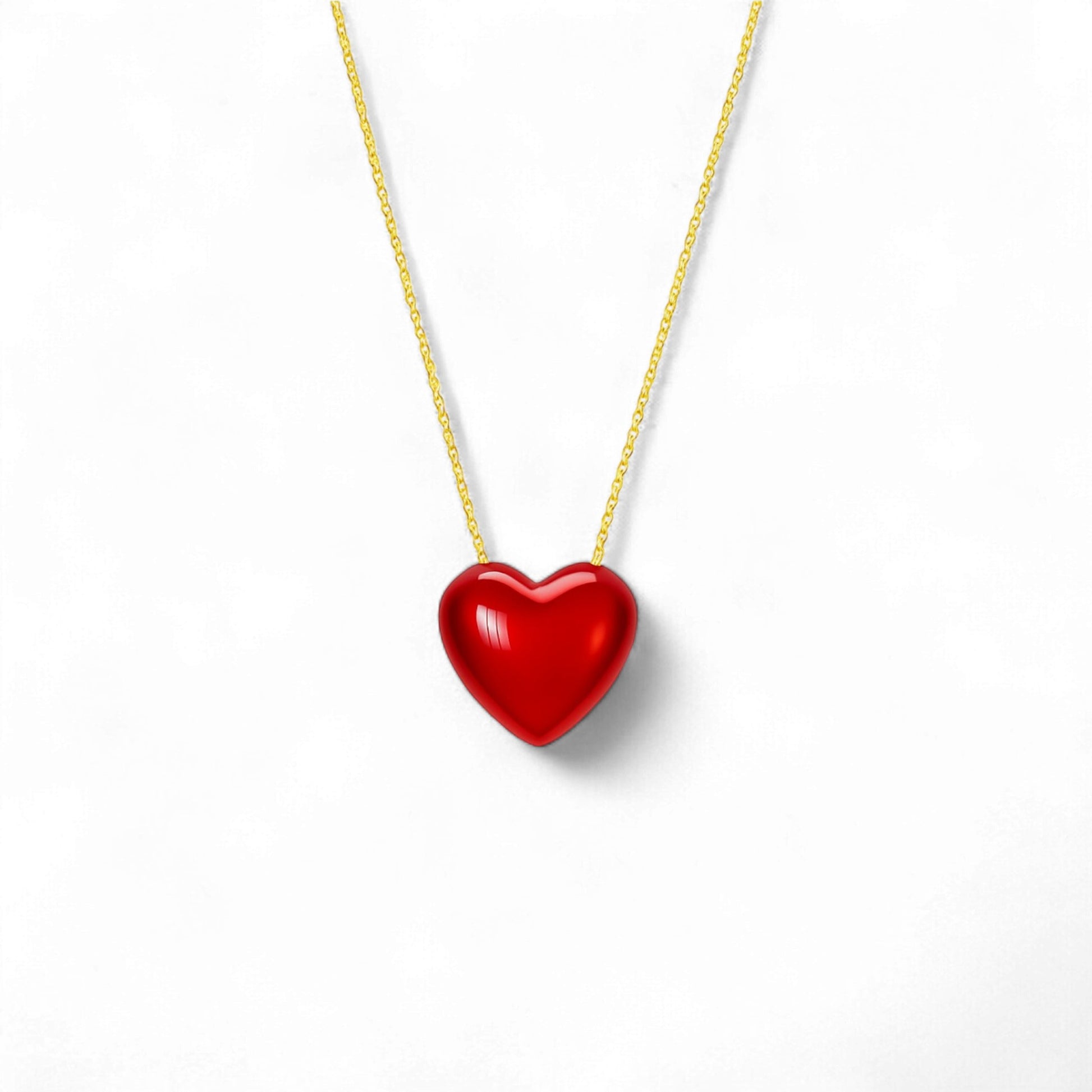 Red heart-shaped pendant on a gold chain against a white background