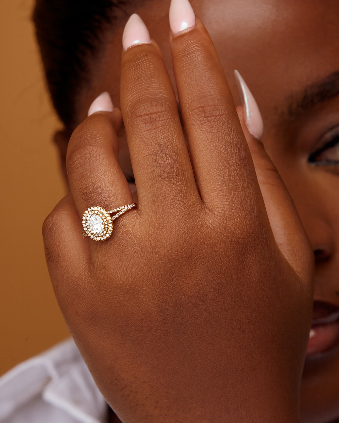 A person showcasing an oval cut moissanite and diamonds engagement ring on their finger.