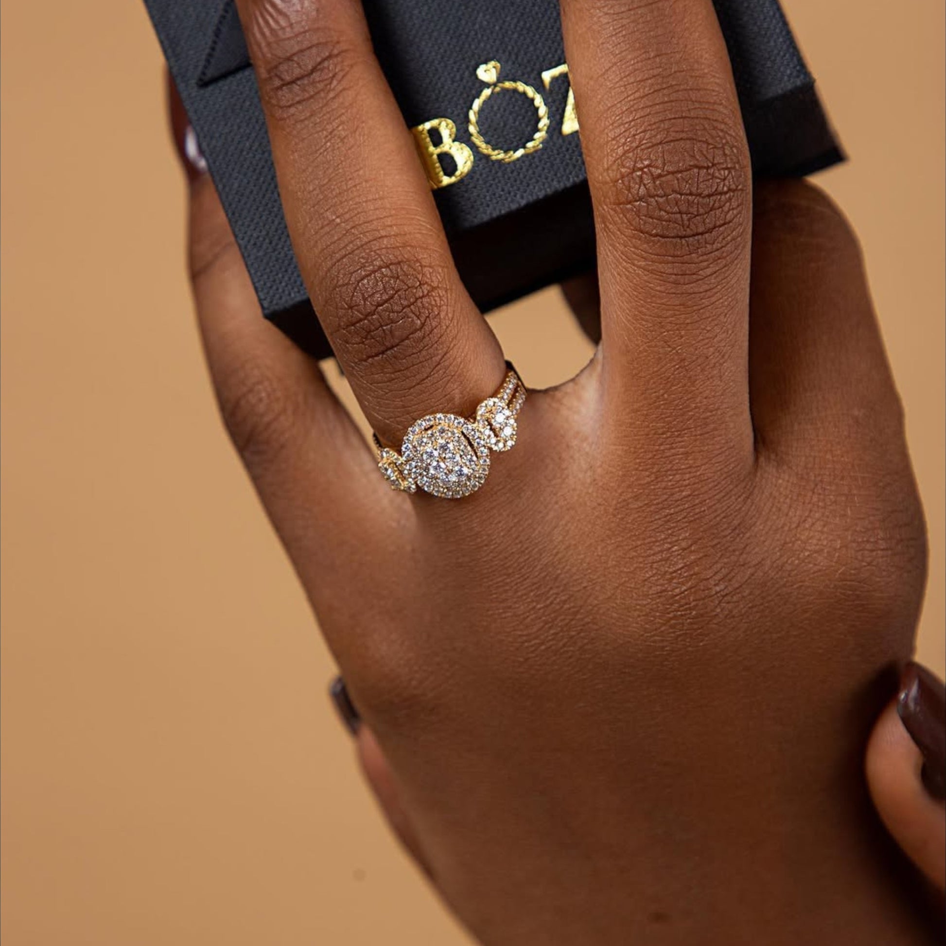 Hand wearing a diamond ring with a Bozzy box in the background