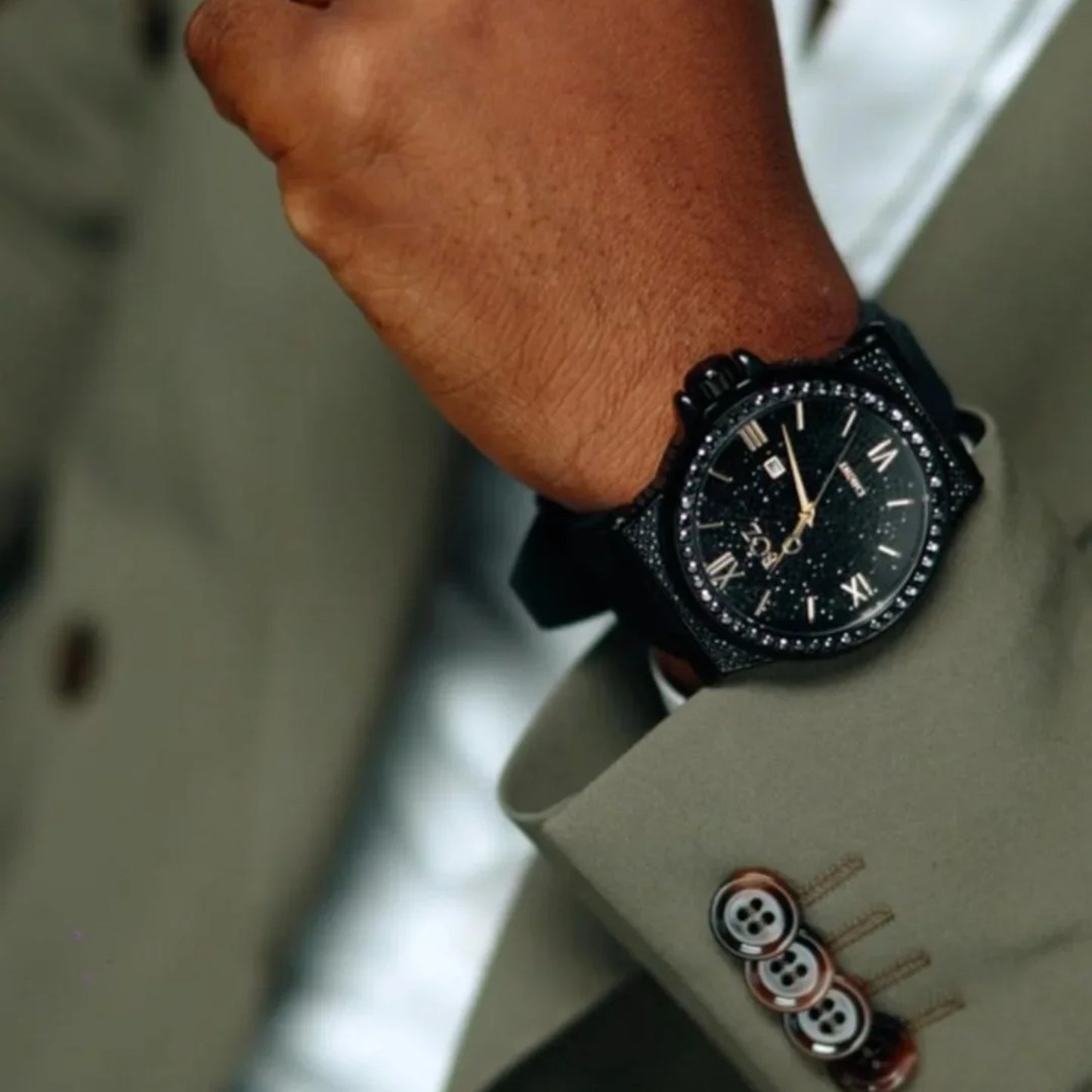 Close-up of a person wearing a black wristwatch with a suit sleeve.