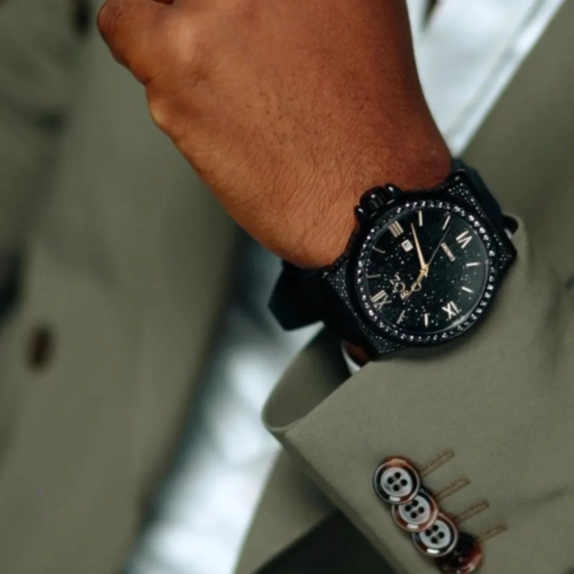 Close-up of a person wearing a black wristwatch with a suit sleeve.