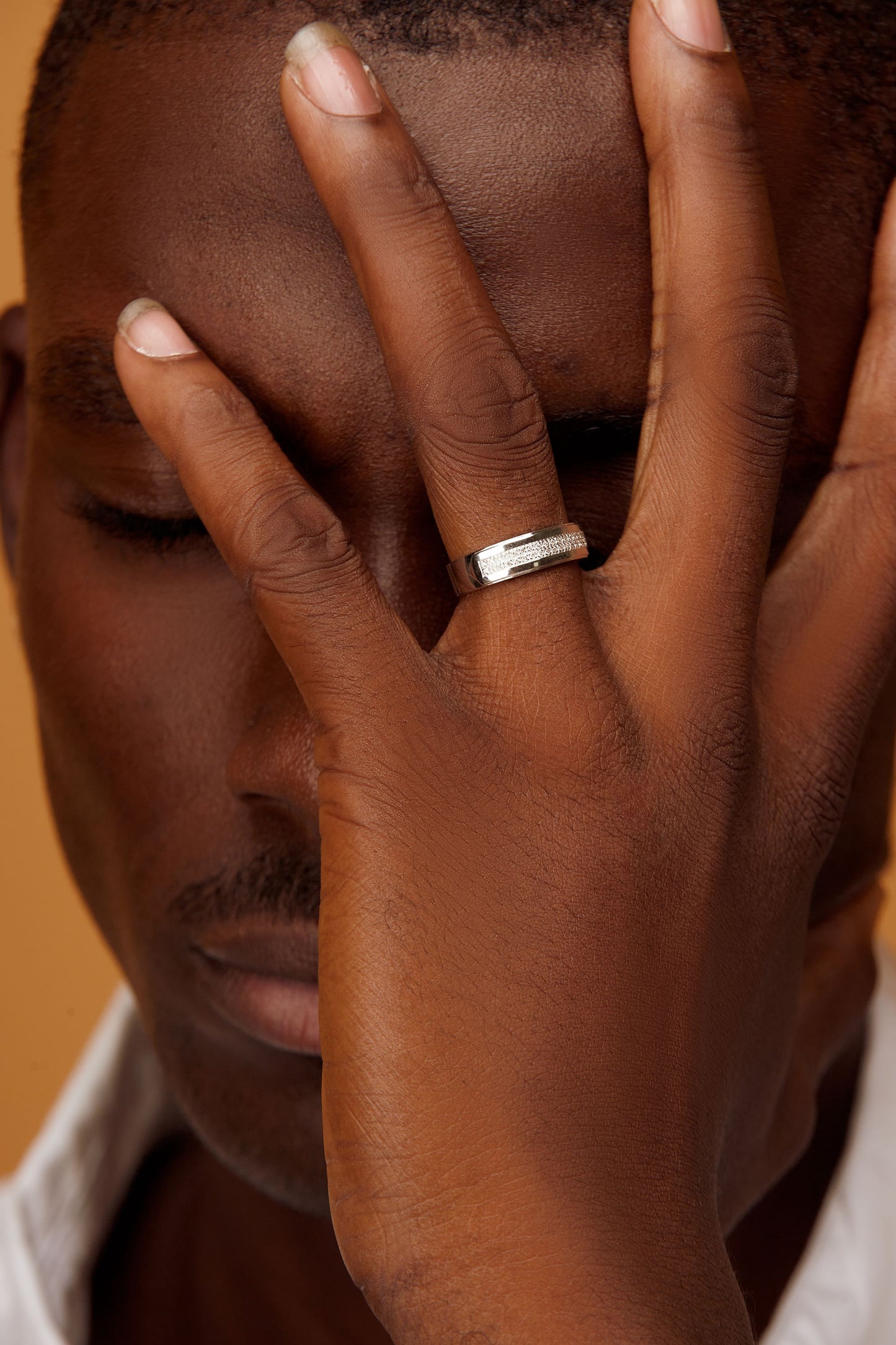 A man's hand displaying a 18K gold ring with a natural diamond on the ring finger.