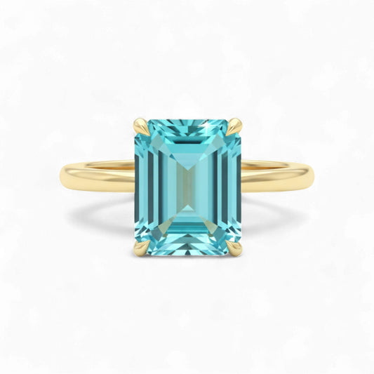 Gold ring with a rectangular blue gemstone on a white background