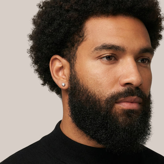 Man with a beard wearing a black turtleneck against a neutral background