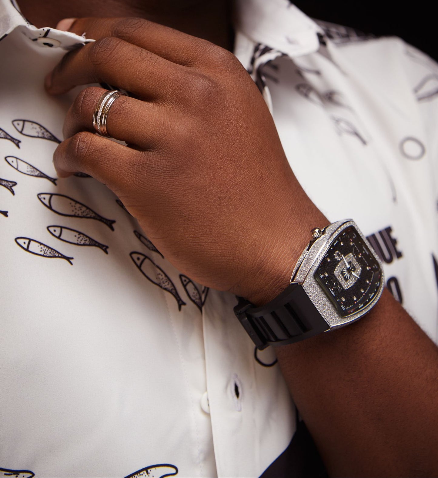 Hand wearing a watch with a patterned shirt in the background