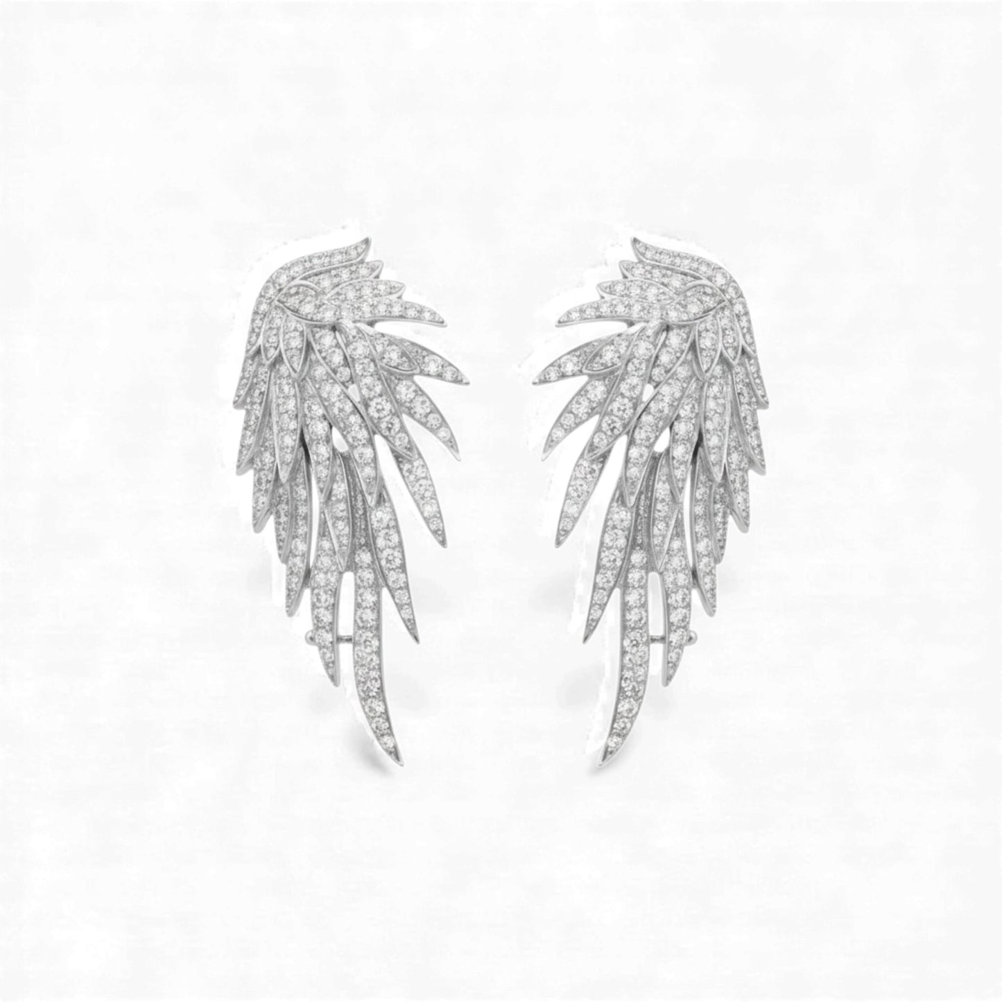 Pair of silver leaf-shaped earrings on a light gray background