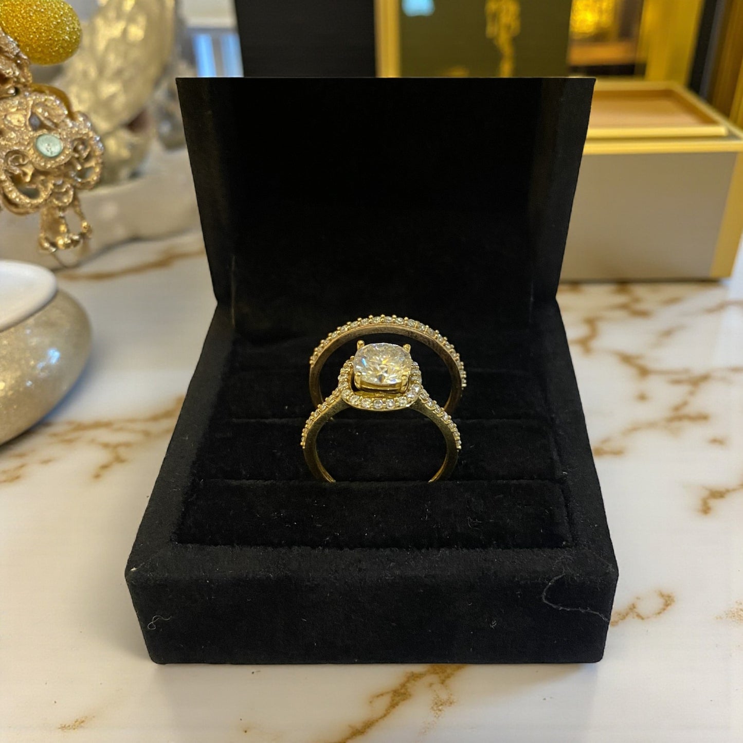 Gold ring with diamond in a black jewelry box on a marble surface