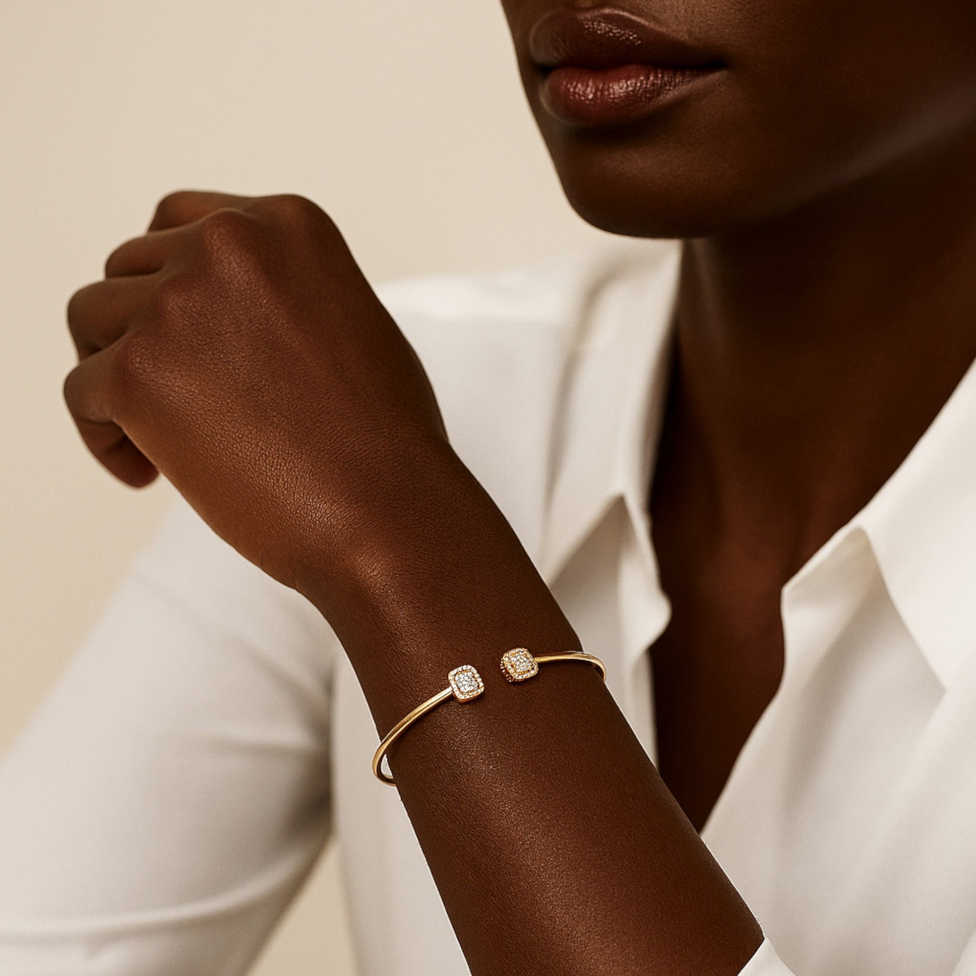 Woman wearing a gold bracelet with diamond accents on a neutral background