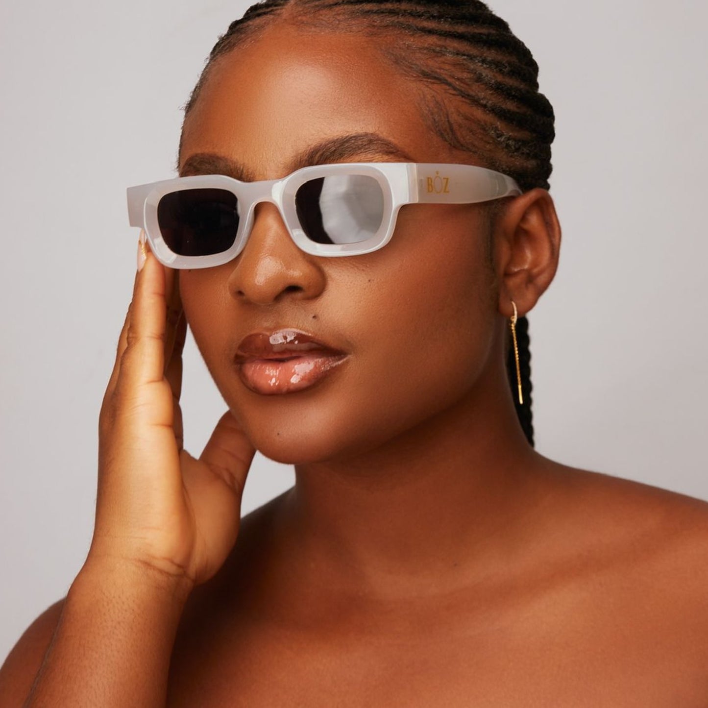 Woman wearing white sunglasses with a neutral background