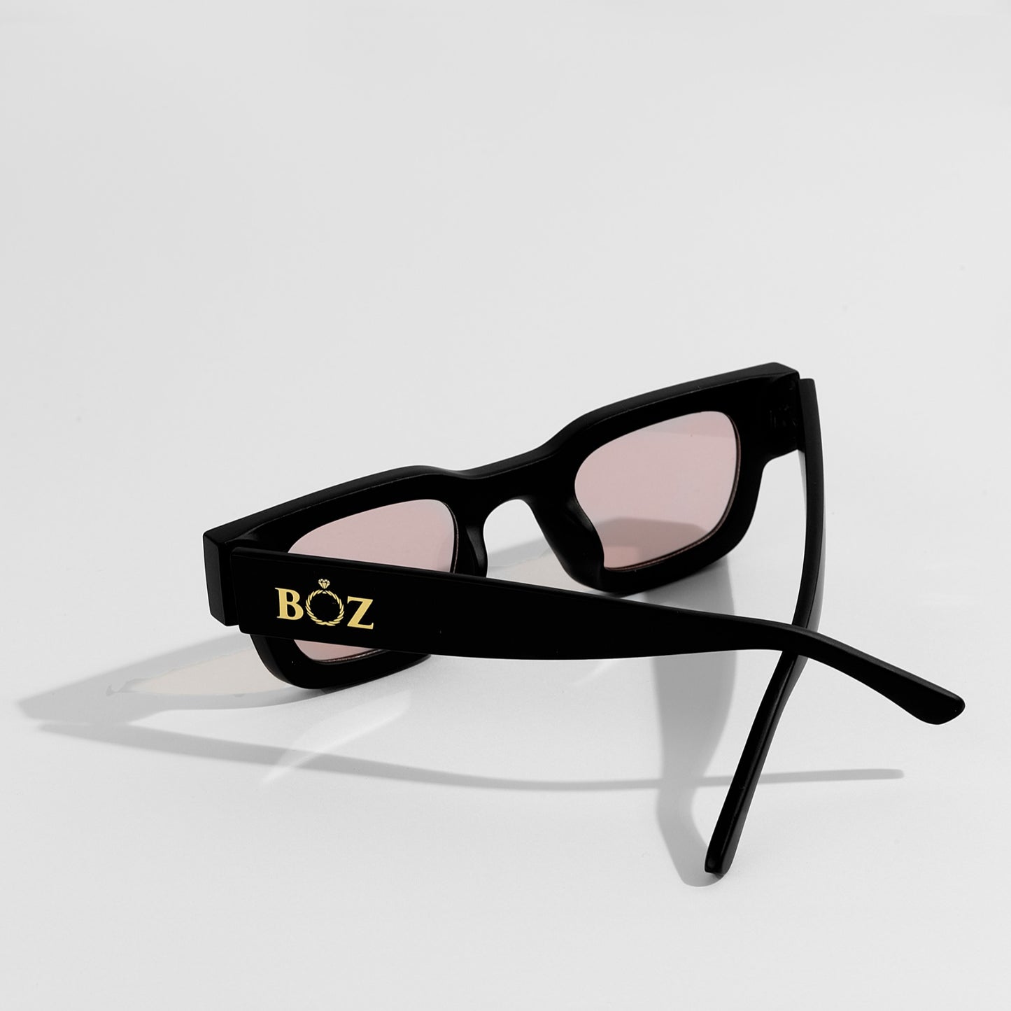 Black sunglasses with pink lenses on a white background, featuring the brand 'BOZ'.