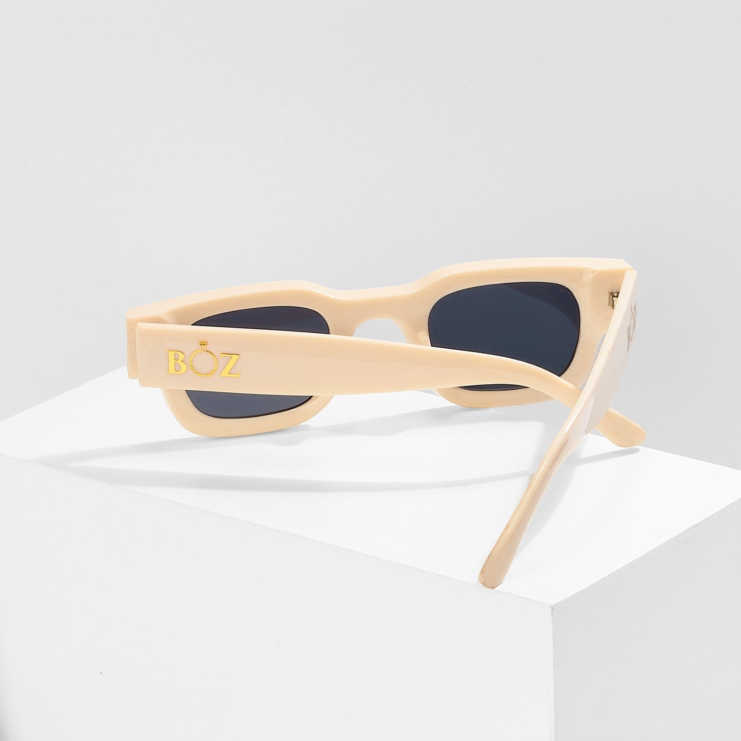 Beige sunglasses with dark lenses on a white background
