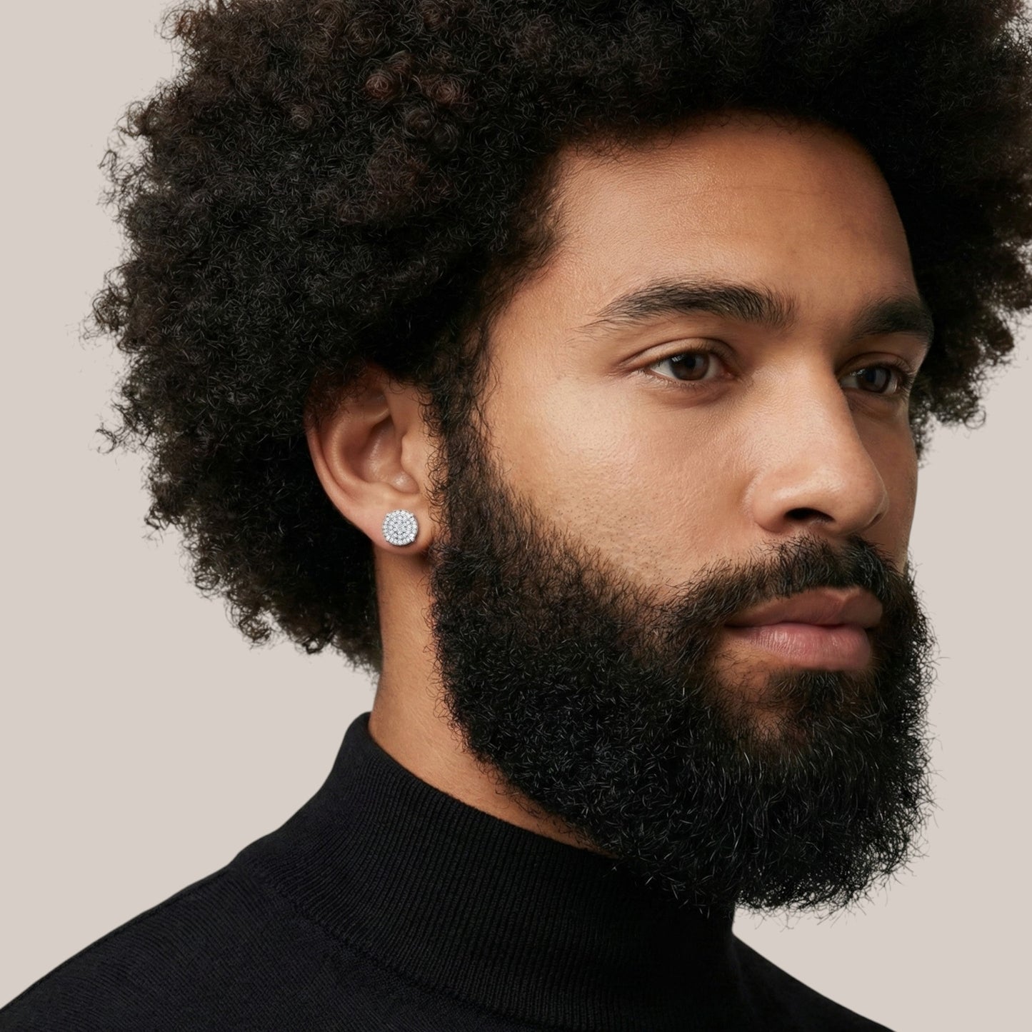 Man with a beard wearing a black turtleneck against a neutral background