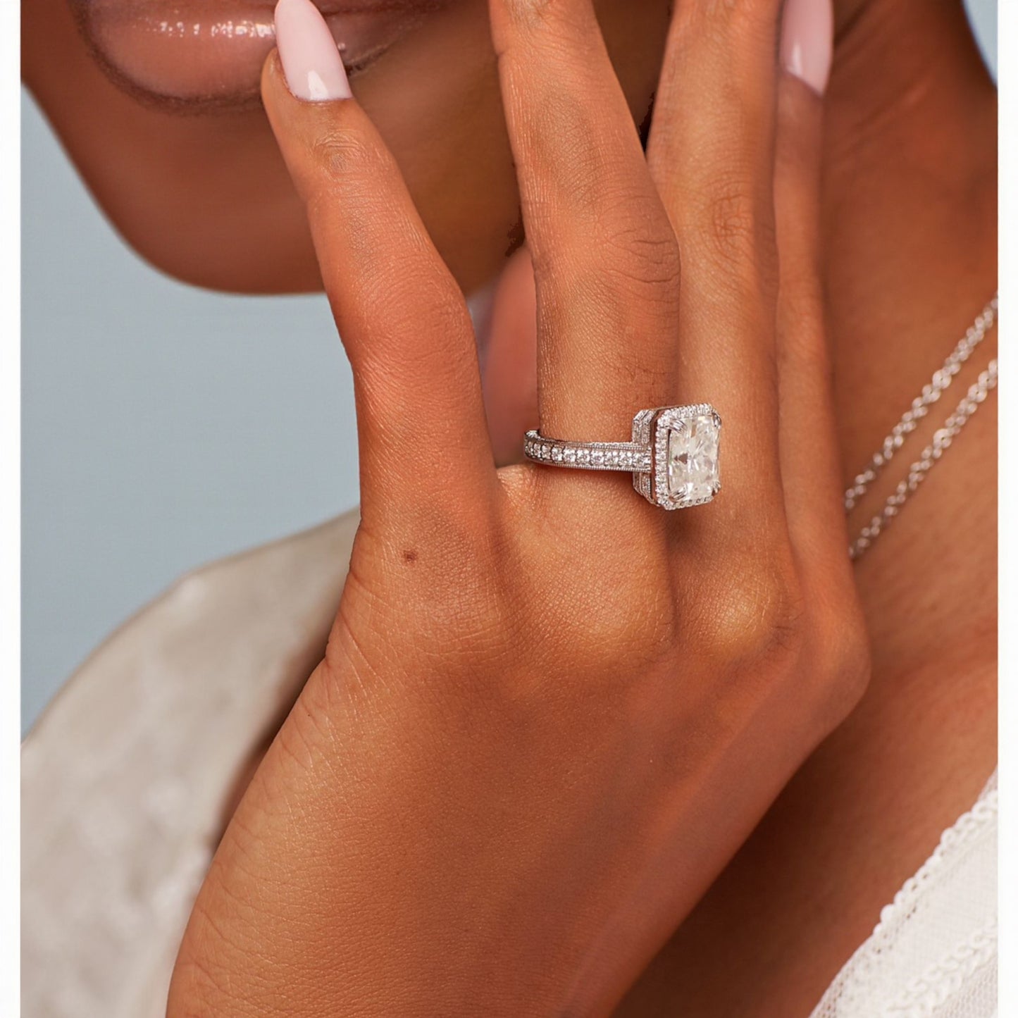 Close-up of a hand wearing a diamond ring with a light background