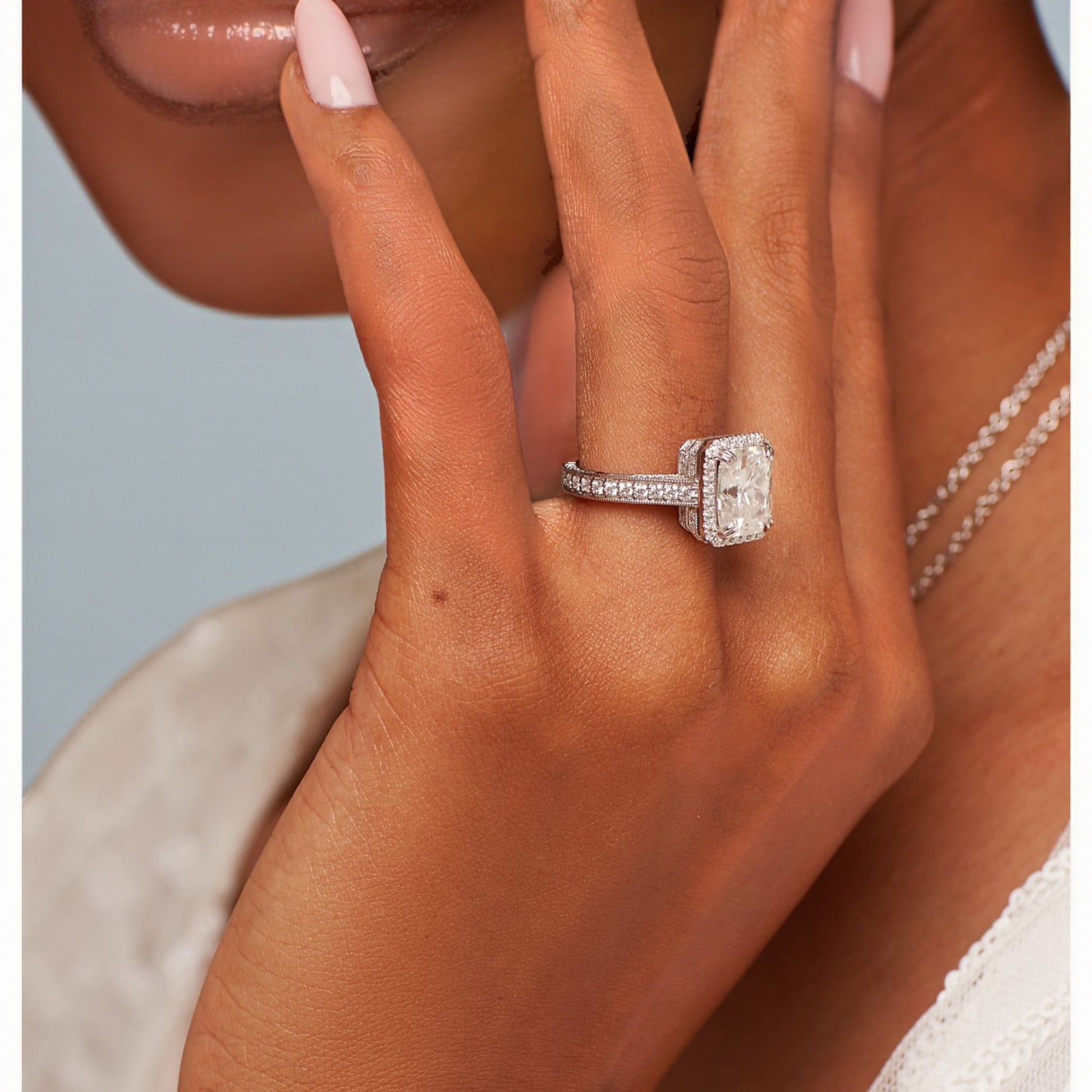Close-up of a hand wearing a diamond ring with a light background