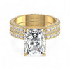 Gold ring with a large diamond and smaller diamonds on the band against a white background