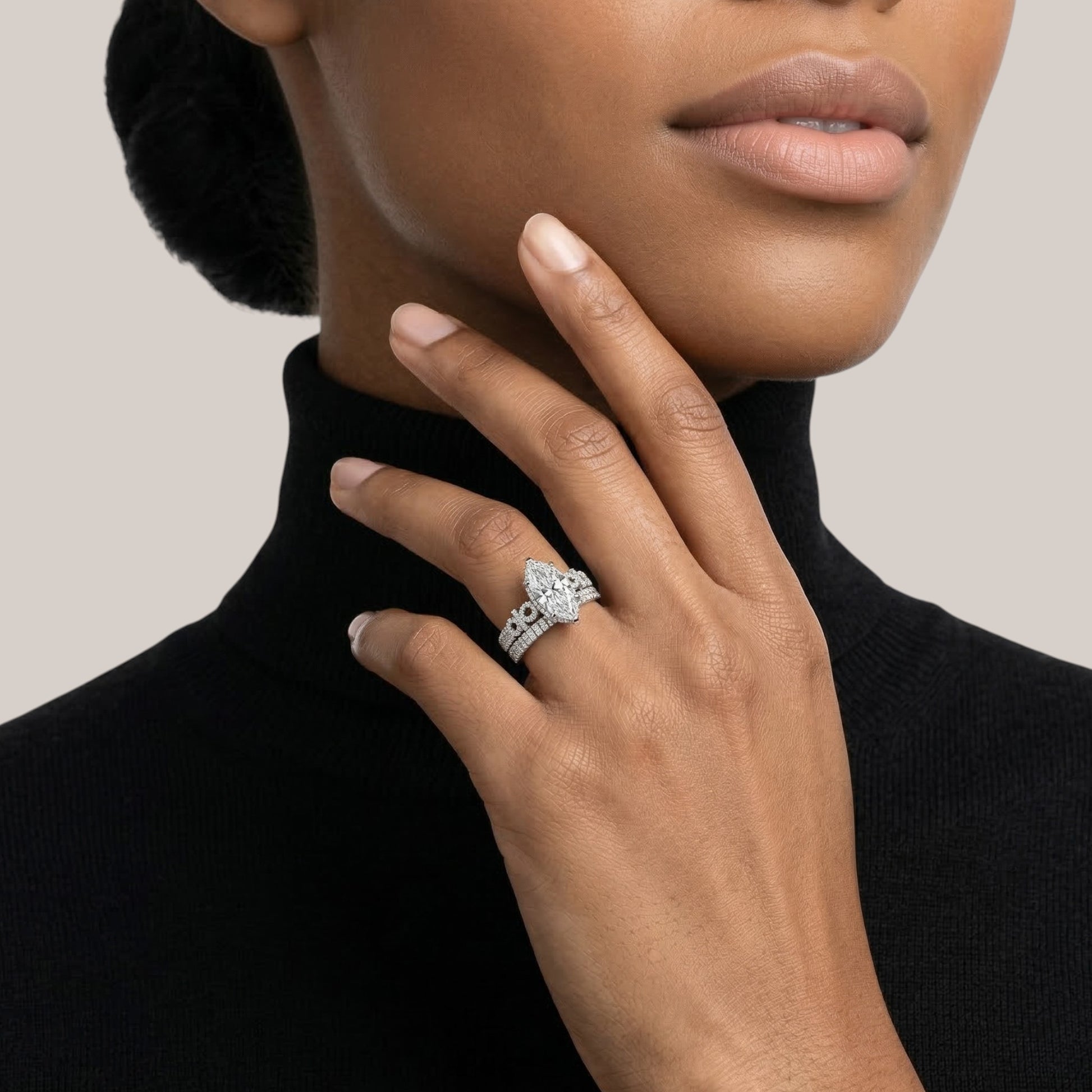 Close-up of a woman wearing a diamond ring on a neutral background
